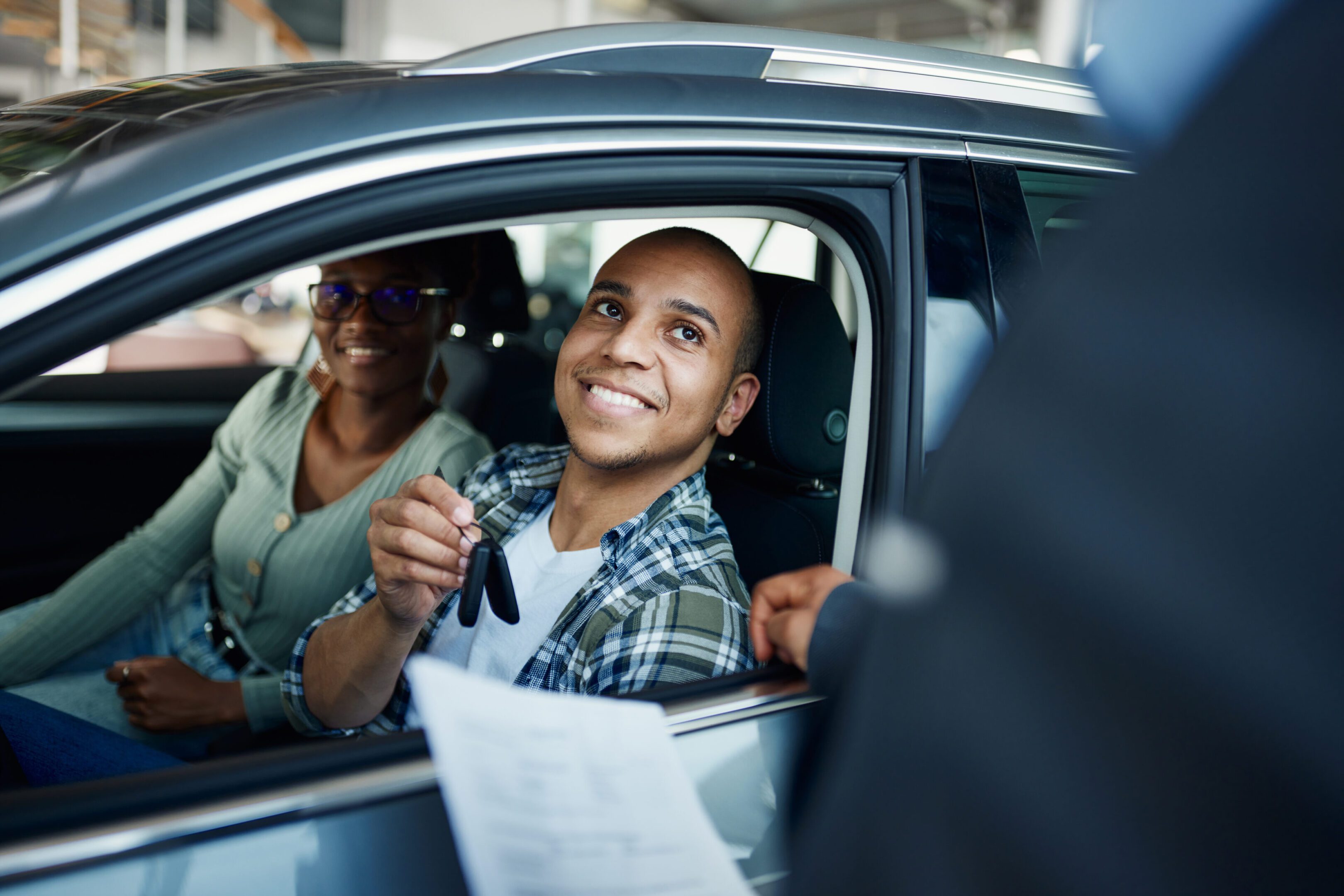 Man holding car keys, sitting in vehicle.